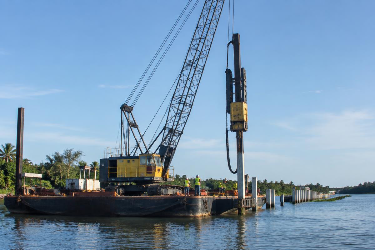 Crane barge driving concrete marine pilings along a Florida waterway